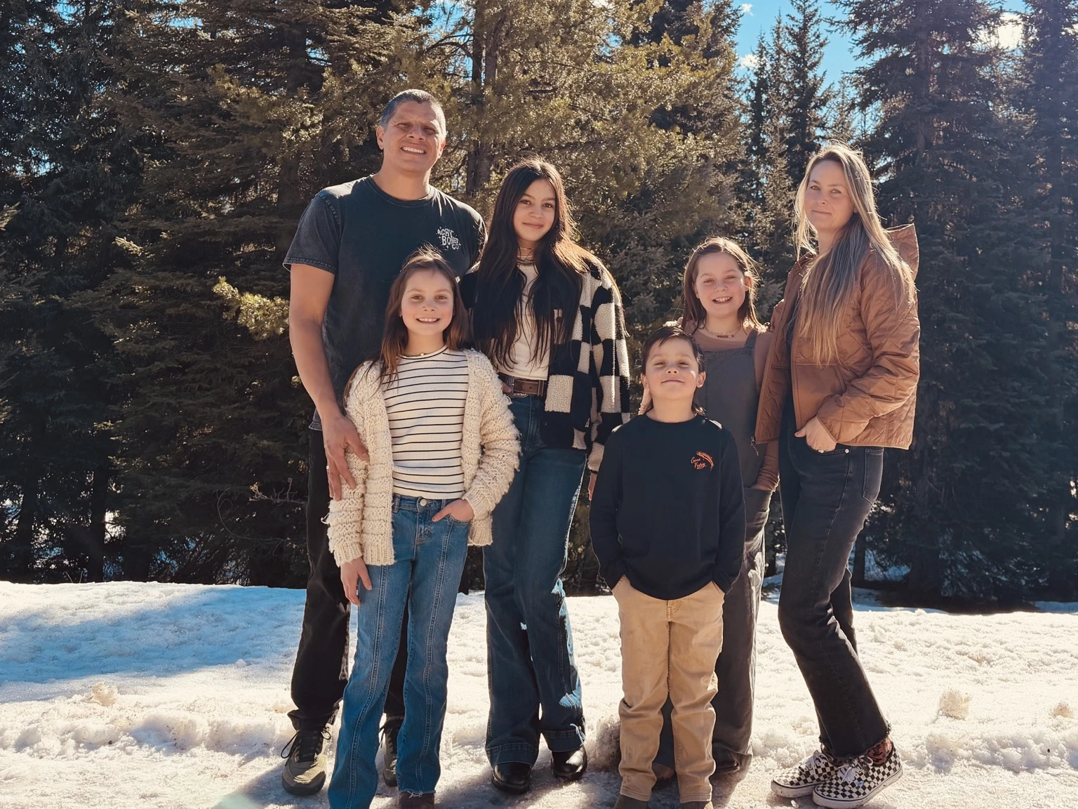 The family behind White Sands Spa Repair standing together outdoors among evergreen trees